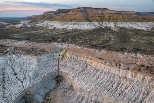 Aerial view of the dramatic white limestone cliffs and eroded canyons of the Tuzbair salt flats in the vast desert landscape of Mangystau District, Mangystau Region, Kazakhstan.