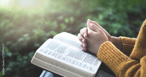 Fotografie Hands folded over an open Bible, representing daily worship, Scripture meditation, spiritual growth, hope, divine guidance, and a deep relationship with God