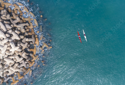 Aerial view of two kayaks paddling near the concrete breakwater of Herzliya Beach in Herzliya, Tel Aviv District, Israel.