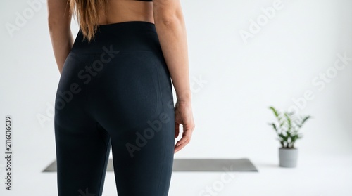 Rear View Close Up of Woman in Black Leggings and Sportswear Standing in Bright Studio