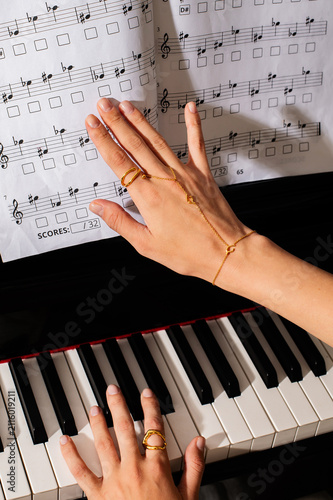 pianist female hands wearing jewelry playing piano and music notes 