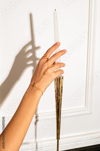 female long woman hand holding a candle in front of the black piano and music notes in the white cosy room