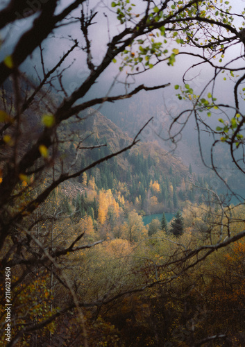 Autumn landscape at Lake Issyk with turquoise water, colorful yellow trees and mountain background in Kazakhstan