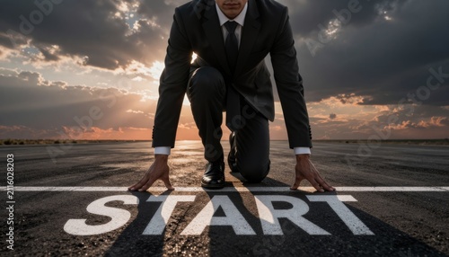 Businessman in Starting Block Stance on Race Track at Sunset