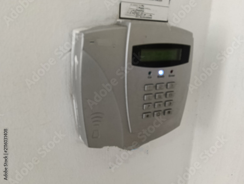 Close-up of a wall-mounted electronic security alarm keypad with an LCD display, numeric keypad, LED status indicators, and RFID access symbol. Commonly used in homes, offices, and commercial building