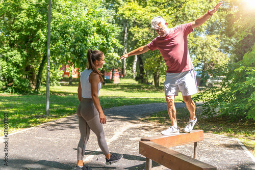 Fotografie Senior man practicing stability and coordination on a balance beam with expert supervision to strengthen balance, improve functional movement, and support healthy active aging