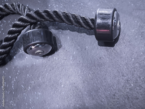 Foto High-angle view of a black gym triceps rope attachment lying on a speckled gray rubber floor in a fitness center