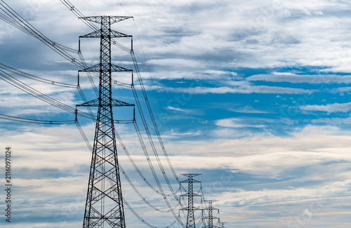 Obraz na plátně High voltage electricity transmission towers and power lines beneath a blue cloudy sky
