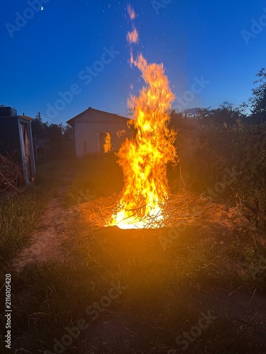 a large evening bonfire against the backdrop of the darkening day