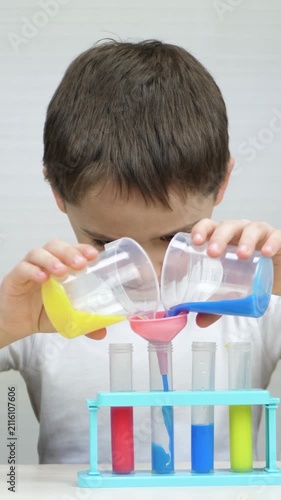 Happy boy performs colorful laboratory experiment by mixing liquids in flask. Vertical video highlights experiential learning, scientific curiosity, problem solving and excitement of discovery.