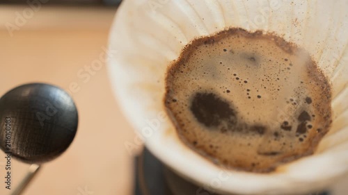 Pour over coffee brewing close up, drip filter coffee with bubbles macro shot, barista pouring hot water over ground coffee, specialty coffee preparation