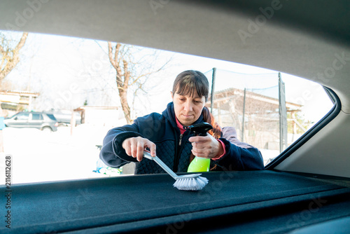Obraz na płótnie Cleaning the interior of a car while using a brush and spray bottle