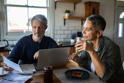 Middle-aged couple paying bills at kitchen table