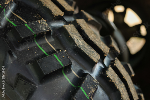 New off road tire tread with green factory stripe and dirt speckle, rugged rubber pattern close up showing chunky lugs and texture conveying adventure and utility