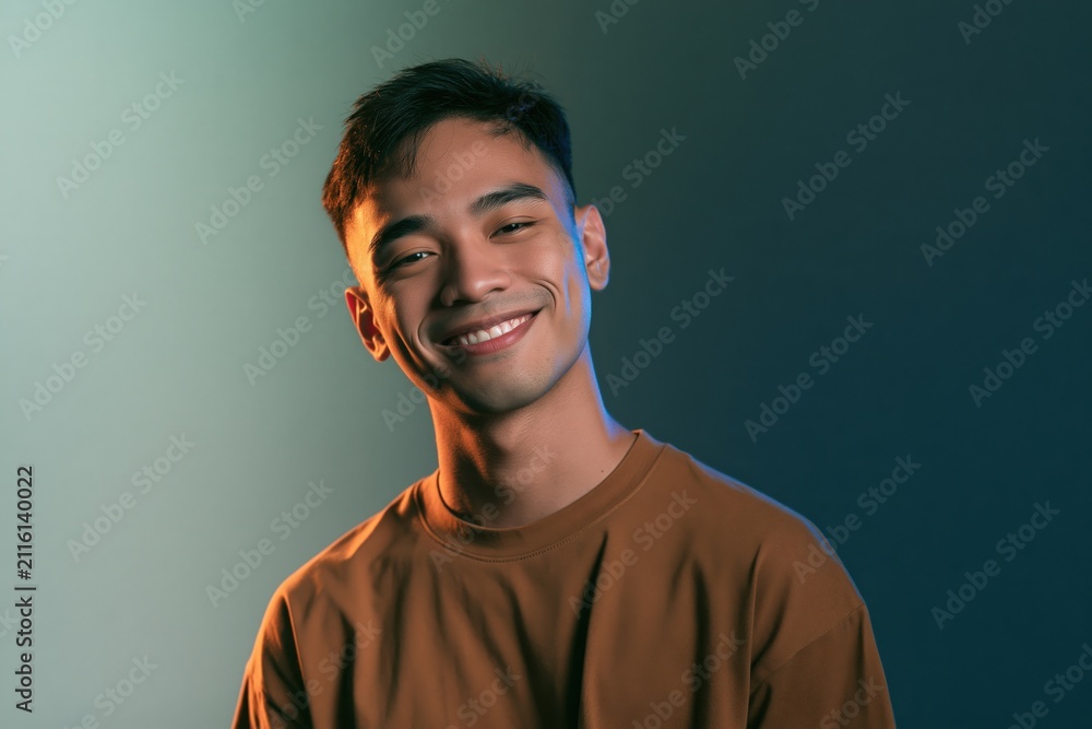 Fototapeta premium Smiling young man headshot with soft blue studio rim light for casual portrait background and profile banner design