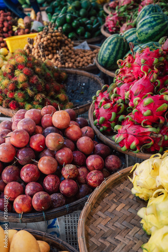 Variety of tropical fruits arranged at a market stall, featuring dragon fruit, watermelon, passion fruit and exotic produce.