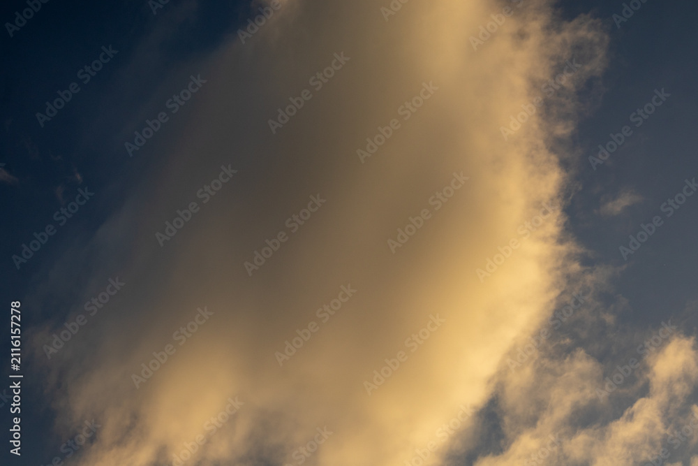 Fototapeta premium Golden Cloud Against a Dark Blue Sky
