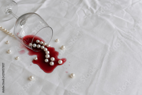 infidelity. Overturned red wine glass and scattered pearls on crumpled white tablecloth, scandal and infidelity concept, bar promotions.