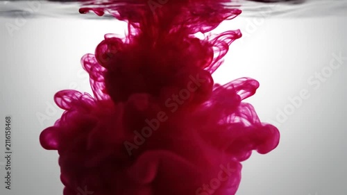 Single red drop falling into white liquid surface.