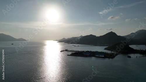 Sunlight reflecting on calm sea by coastal mountains at sunset