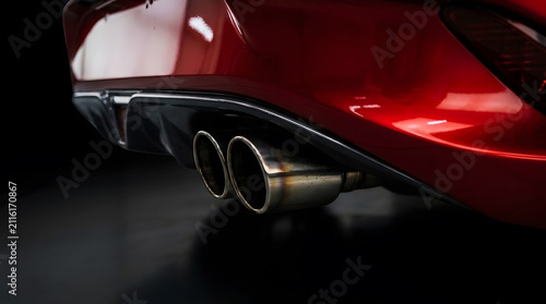 Close-up of Stainless Steel Twin Exhaust Pipes on Red Sports Car Bumper