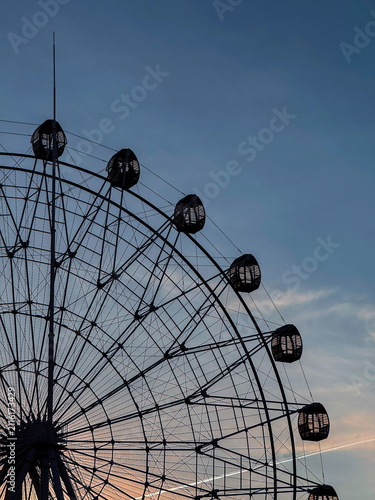Low angle view of Ferris wheel silhouette at sunset with twilight sky background