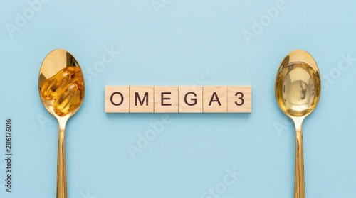 Two golden spoons hold omega-3 capsules on either side of wooden tiles spelling 