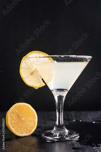 Martini glass with lemon slice on rim, dark background