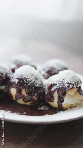 Close-up of profiteroles with chocolate sauce on white plate