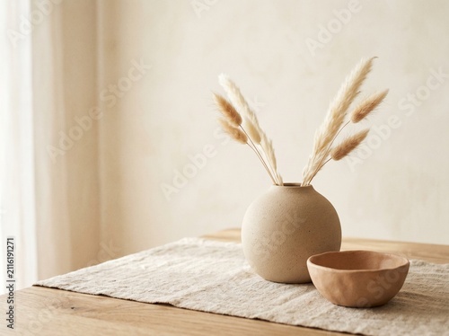Minimalist vase with pampas grass. Neutral home decor with dried flowers on a wooden table.