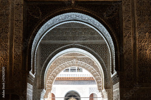 intricate Moorish architecture and horseshoe arches adorned with elaborate stucco work inside the Nasrid Palaces at the Alhambra in Granada, Spain.