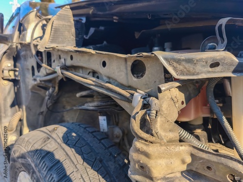 Closeup of exposed front chassis and suspension components on a dismantled vehicle undergoing collision repair and mechanical restoration work