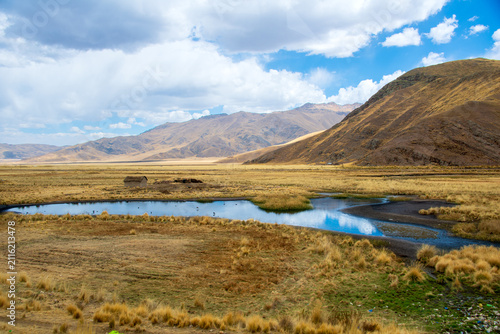Scenic Andean Altiplano Landscape with Reflective Blue Water Pond and Mountain Range Under Blue Sky