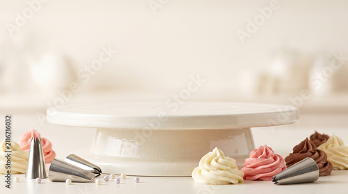Ceramic cake turntable with frosting swirls and metal piping tips on a bright kitchen background
