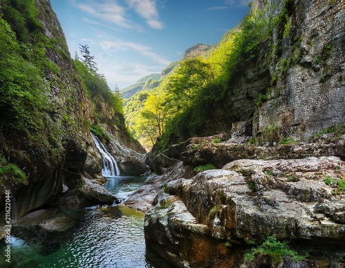 rugged rock formations create a natural gorge with a flowing stream and small waterfalls