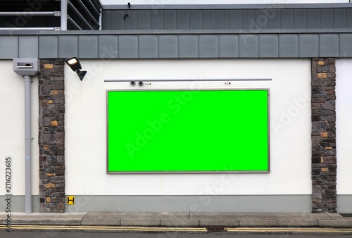 Blank billboard advertisement. Empty chroma green advertisement with copy space on a generic city supermarket building in Europe.