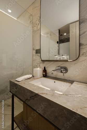 фотографія Modern bathroom vanity with marble countertop, sink, and mirror in a luxury home or hotel interior