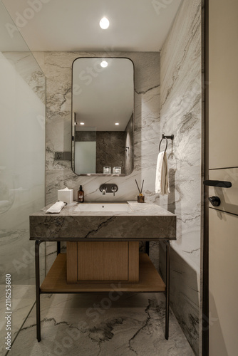 фотографія Modern bathroom interior with marble vanity, mirror, sink, and beige door in luxury apartment or hotel