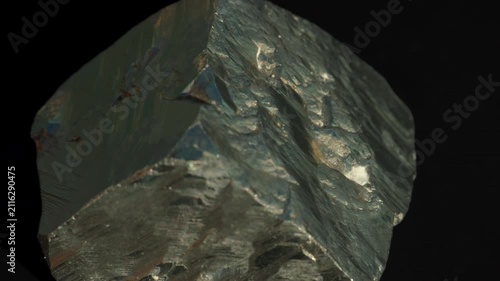 A cubic crystals of pyrite, with some surfaces showing characteristic striations, isolated on a black background