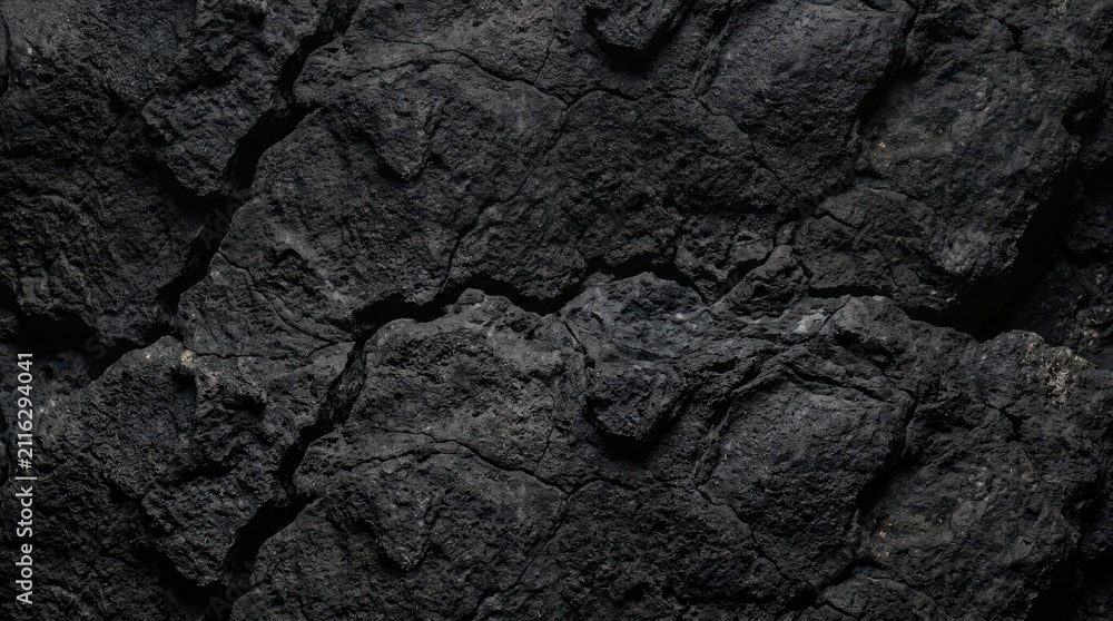 Dark black cracked earth texture background showing dry soil surface with deep fissures and rugged geological patterns