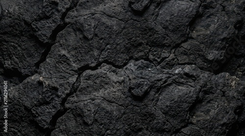 Dark black cracked earth texture background showing dry soil surface with deep fissures and rugged geological patterns