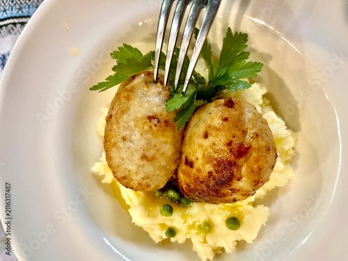 Canvastavla Plate of tender mixed meat cutlets made from rabbit, chicken, and turkey, served with creamy mashed potatoes, green peas, and fresh herbs