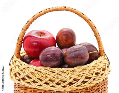 Fresh apples and plums in a basket on white background.