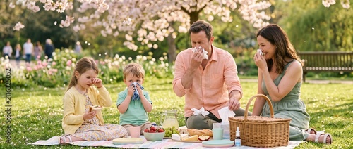 Family enjoying picnic outdoors in spring with mild allergy symptoms  