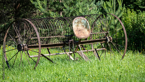 Fotografie Vintage rusty agricultural hay rake in green grass field