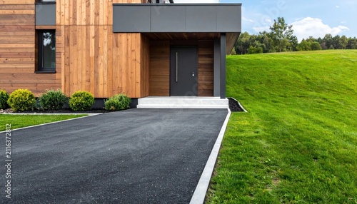 Modern Wooden House with Asphalt Driveway and Lush Green Lawn.