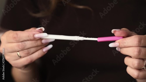 Woman displays pregnancy test in hands, highlighting the gradual appearance of test lines in a close-up view with soft lighting