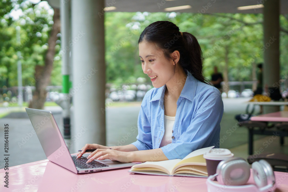 Fototapeta premium Education, university and woman in campus, research and books for school project or exam. Laptop, notebook and internet, college student studying with technology and e learning on campus