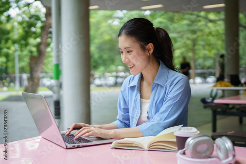 Education, university and woman in campus, research and books for school project or exam. Laptop, notebook and internet, college student studying with technology and e learning on campus