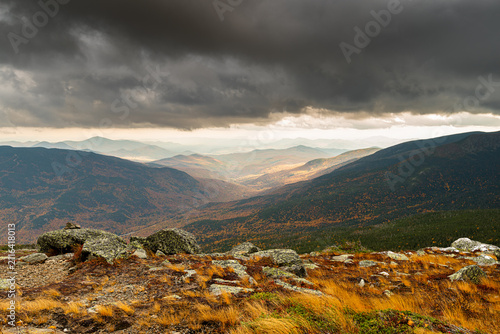 Dramatic mountain landscape with dark storm clouds and autumn foliage
